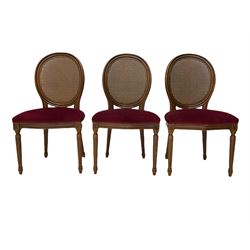 Set six French style walnut finish dining chairs, oval cane bergere backs over serpentine seats upholstered in red, flower head carved fluted supports