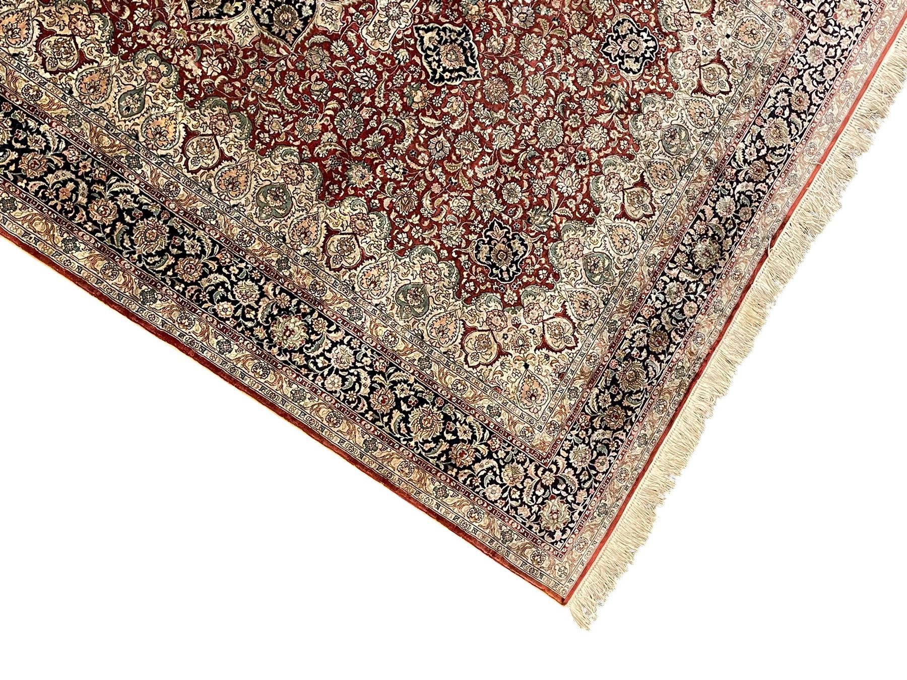 Persian silk finely knotted rug, central floral rosette medallion surrounded by curling branches decorated with palmettes, repeating pattern borders decorated with stylised plants and trailing leafy branches  