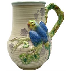 Clarice Cliff baluster jug moulded with a blue budgerigar perched upon branch with green rustic handle and mushroom glaze,  factory stamped beneath, H22.5cm