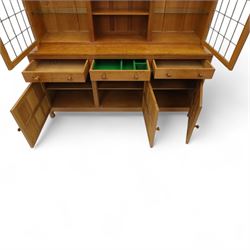 David 'Oakleafman' Langstaff - oak three drawer dresser, the scalloped cornice above a back with central open shelves flanked by two glazed and leaded cupboard doors opening to glass shelves, upon a base with adzed top carved with signature leaf, three drawers and three panelled cupboard doors with turned handles, upon octagonal feet, from the workshop of David Langstaff, Easingwold, Yorkshire