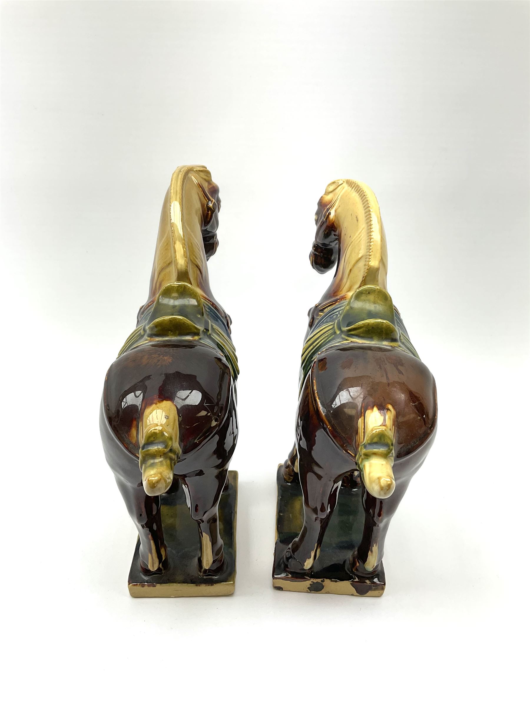 A pair of glazed pottery Tang style horses, each with impressed marks beneath, each approximately H25.5cm. 