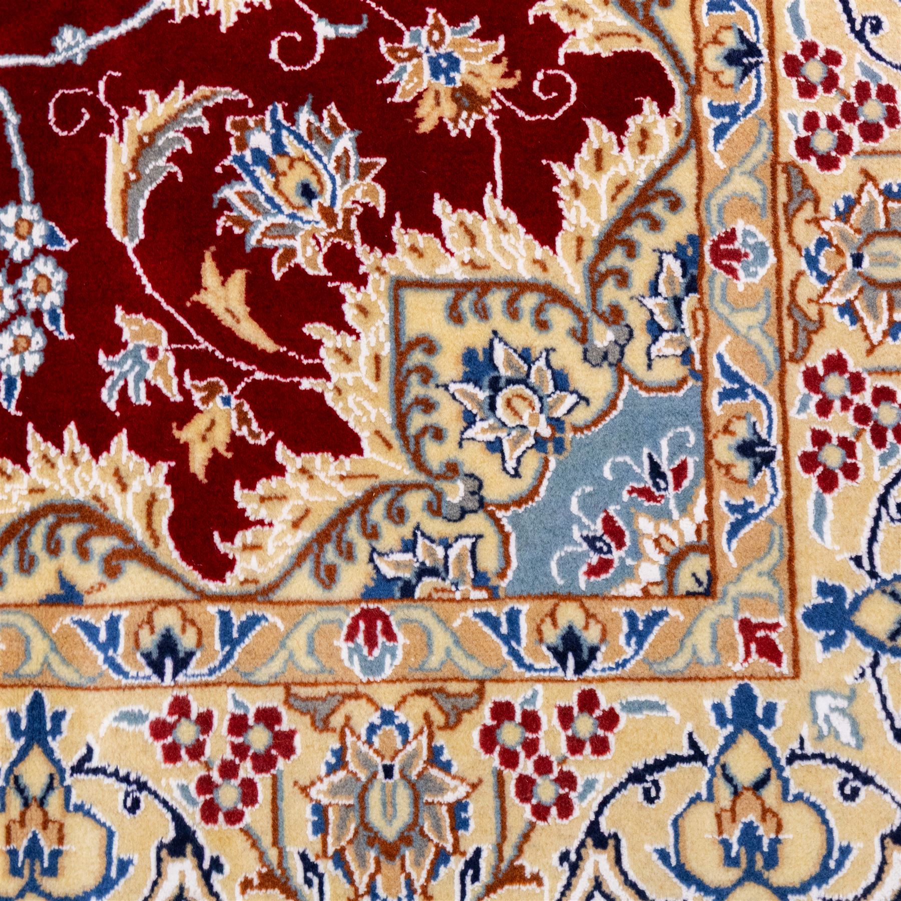 Central Persian Nain hand-knotted rug, crimson field, with central ornate ivory medallion with scrolling arabesques and flowering vine ornaments within a dense floral lattice framed by pale blue corner spandrels and enclosed with an ivory border of scrolling vine and palmette decoration between multiple guard stripes, with cotton fringe ends 