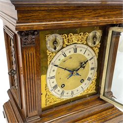 Winterhalder & Hofmeier- German 8-day oak cased mantle clock, in an architectural styled case with a gable pediment and recessed carving to the tympanum, square brass dial flanked by carved reeded pilasters and capitals, with open carved silk backed sound frets on a shaped plinth with padded feet, brass dial with cast spandrels and silvered chapter, Roman numerals, minute track and stylised gothic hands, conforming chime/silent and pendulum regulation dials, twin train going barrel movement with quarter-hour striking on two coiled gongs and the hours on one.
With pendulum.