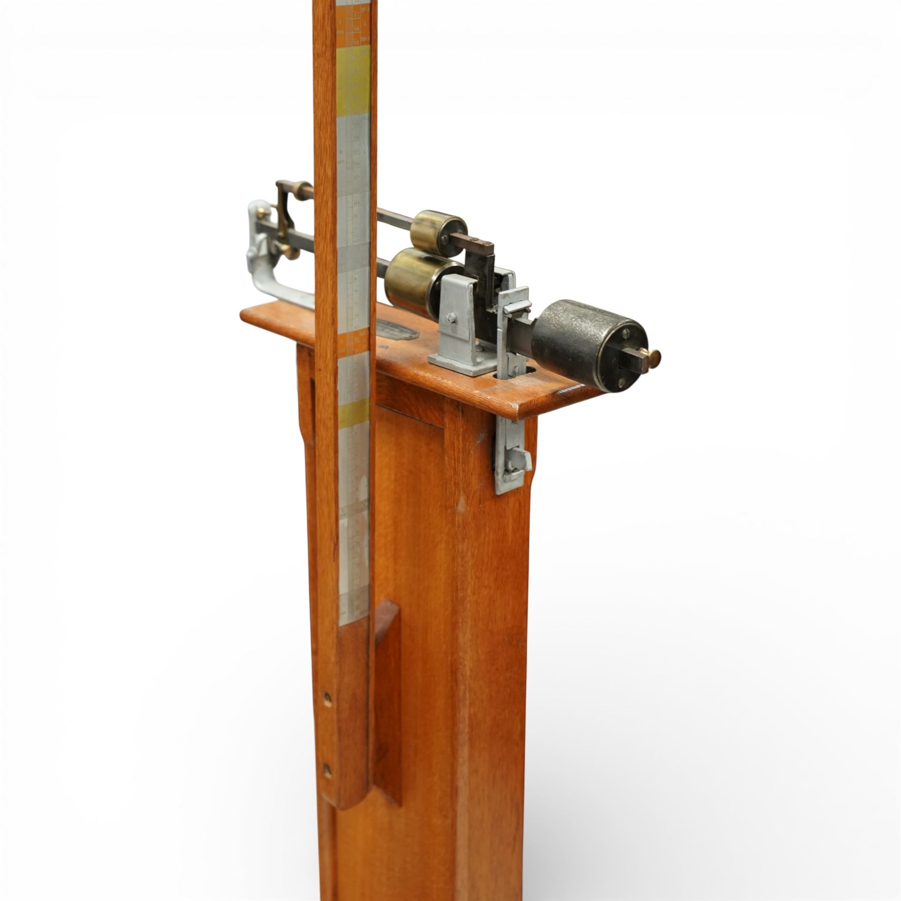 Early 20th century French oak height and balance scales, with graduated vertical rule, adjustable counterweight mechanism with brass and steel fittings, raised on a stepped rectangular oak base, bearing brass maker’s plaque, signed Kuhn & Fleichel, Jarville