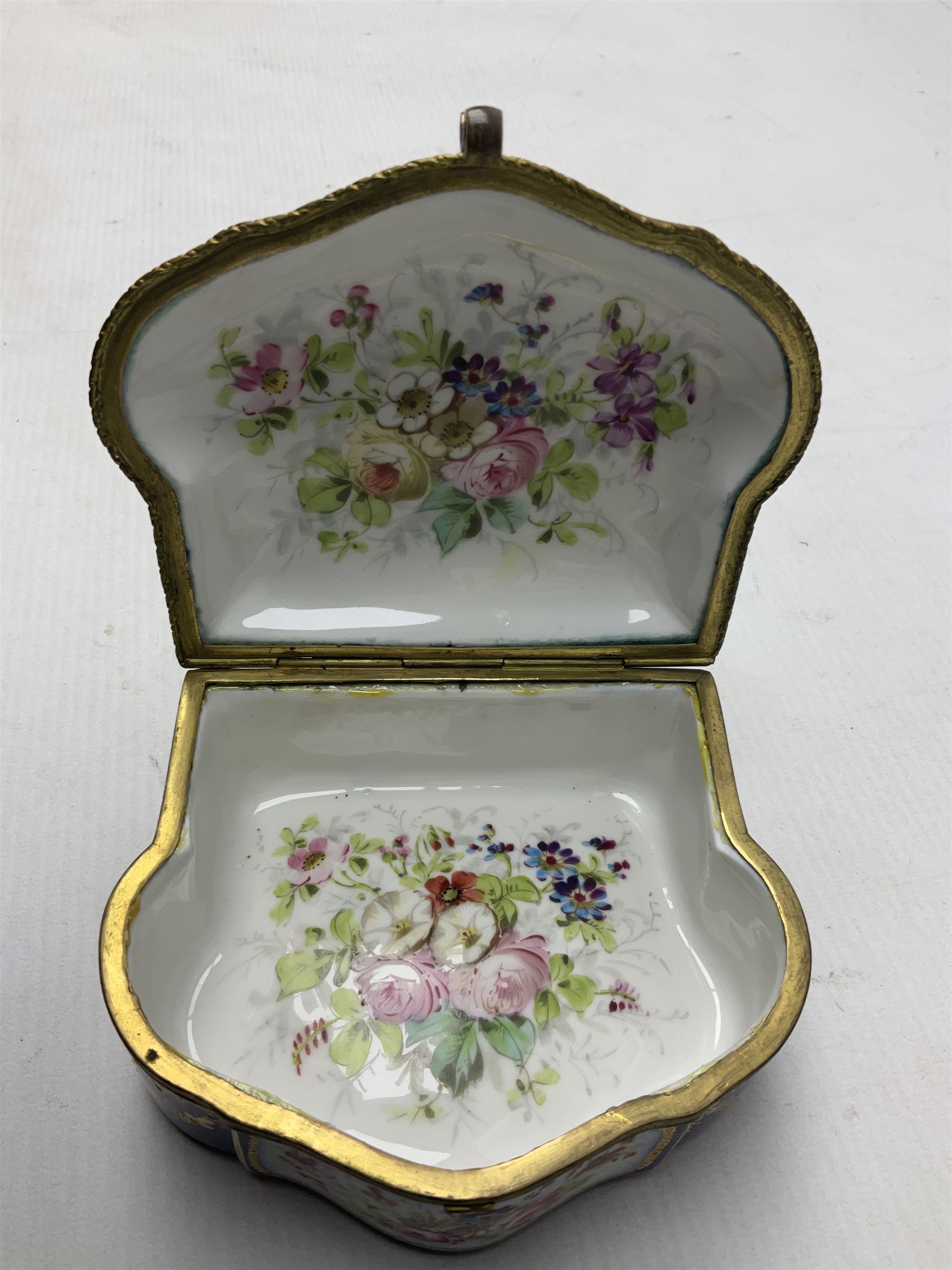 Sevres style late 19th/early 20th century trinket box decorated in the rococo style, the shaped cover painted with an 18th century courting couple in a garden scene opening to reveal the interior painted with floral sprays, the conforming body with a painted panel of floral decoration, all reserved upon cobalt blue ground with foliate gilt borders, with interlaced L's mark beneath, L12cm H6cm