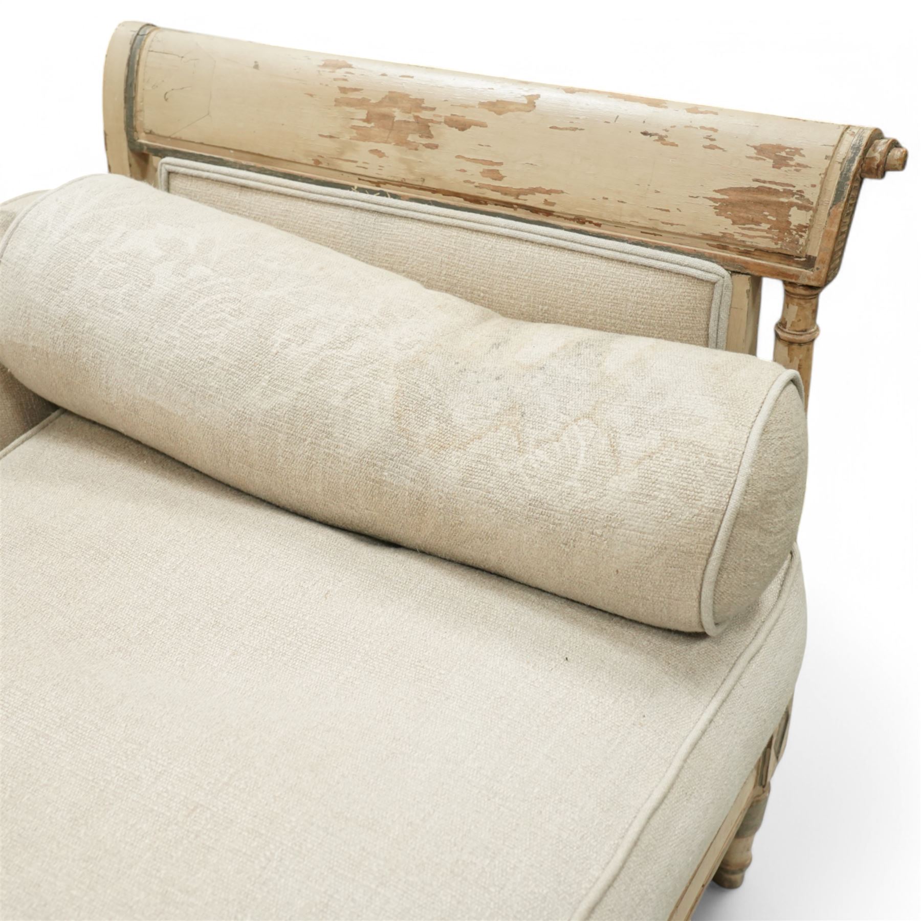 19th Century French day bed, the shaped back and scroll ends with fluted supports and carved rosettes, upholstered in natural linen with loose seat cushions and bolster pillows