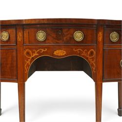 George III inlaid mahogany serpentine sideboard, the shaped top with crossbanding and satinwood stringing, fitted with central bow-front cock-beaded frieze drawer over a shaped apron inlaid with paterae, shell motifs and scrolling foliage, flanked by a deep right-hand drawer and two drawers to the left, raised on square tapering supports with spade feet