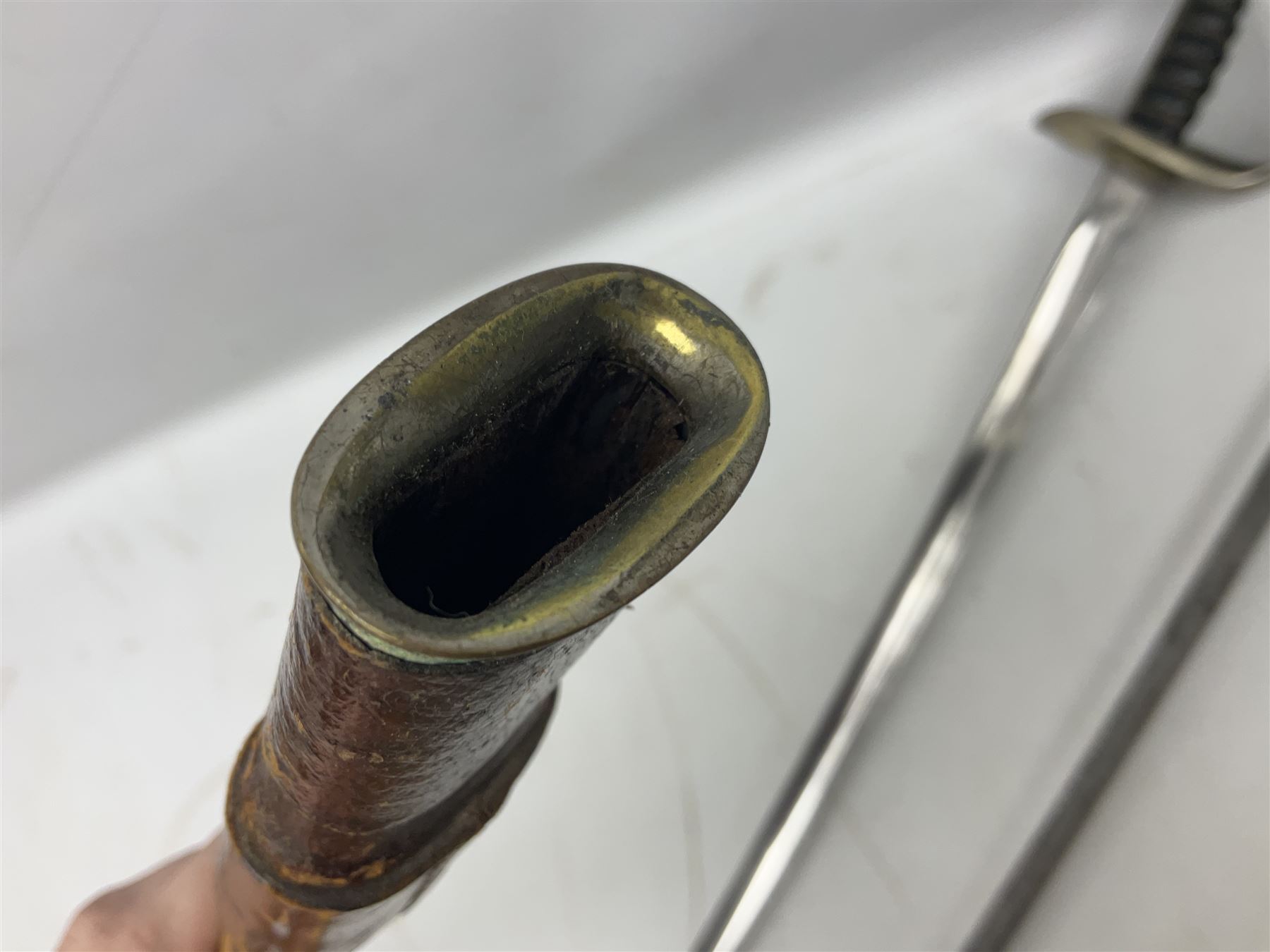 George V British Army 1897 pattern officers sword with plain 82cm fullered steel blade, pierced  basket hilt with George V cypher and wire bound leather grip with chequered backstrap; in leather covered field service scabbard L101cm overall; and another officer's sword in relic condition lacking scabbard (2)