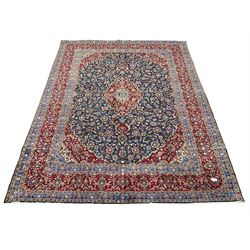 Large Persian Kashan carpet, red and blue ground, the field with central medallion surrounded by interlacing foliate and plant motifs, the border with scrolling design and decorated with flower heads