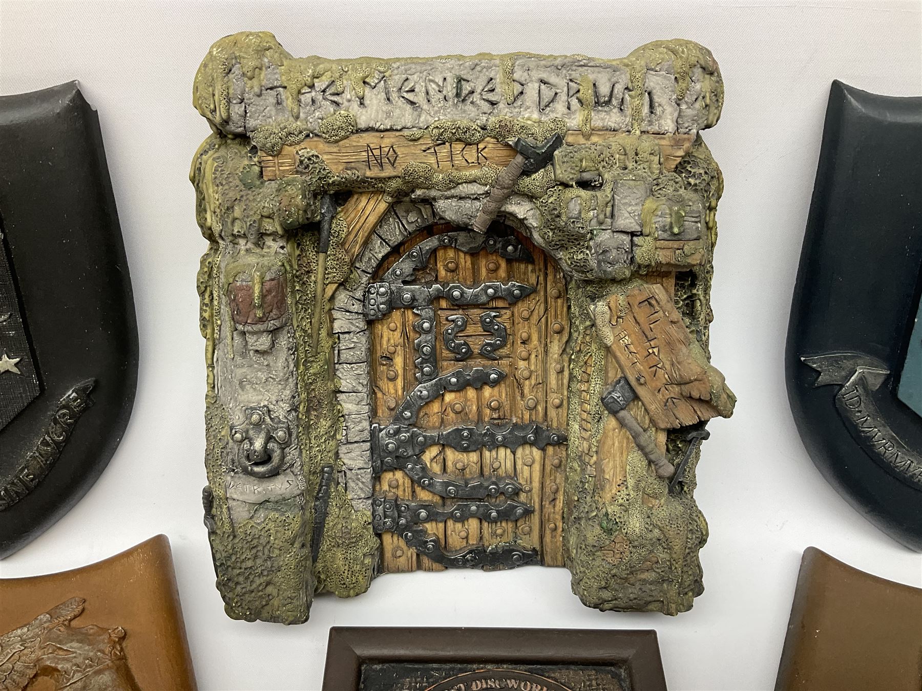 Terry Pratchett Discworld plaques, designed by Clarecraft, comprising 'the First Discworld Event Clarecraft August 95', the collectors guild joining shield, the fools guild DW99C, the seamstresses guild DW98C, the musicians guild DW00C together with 'Door of the mended drum' wall hanging DW17. 