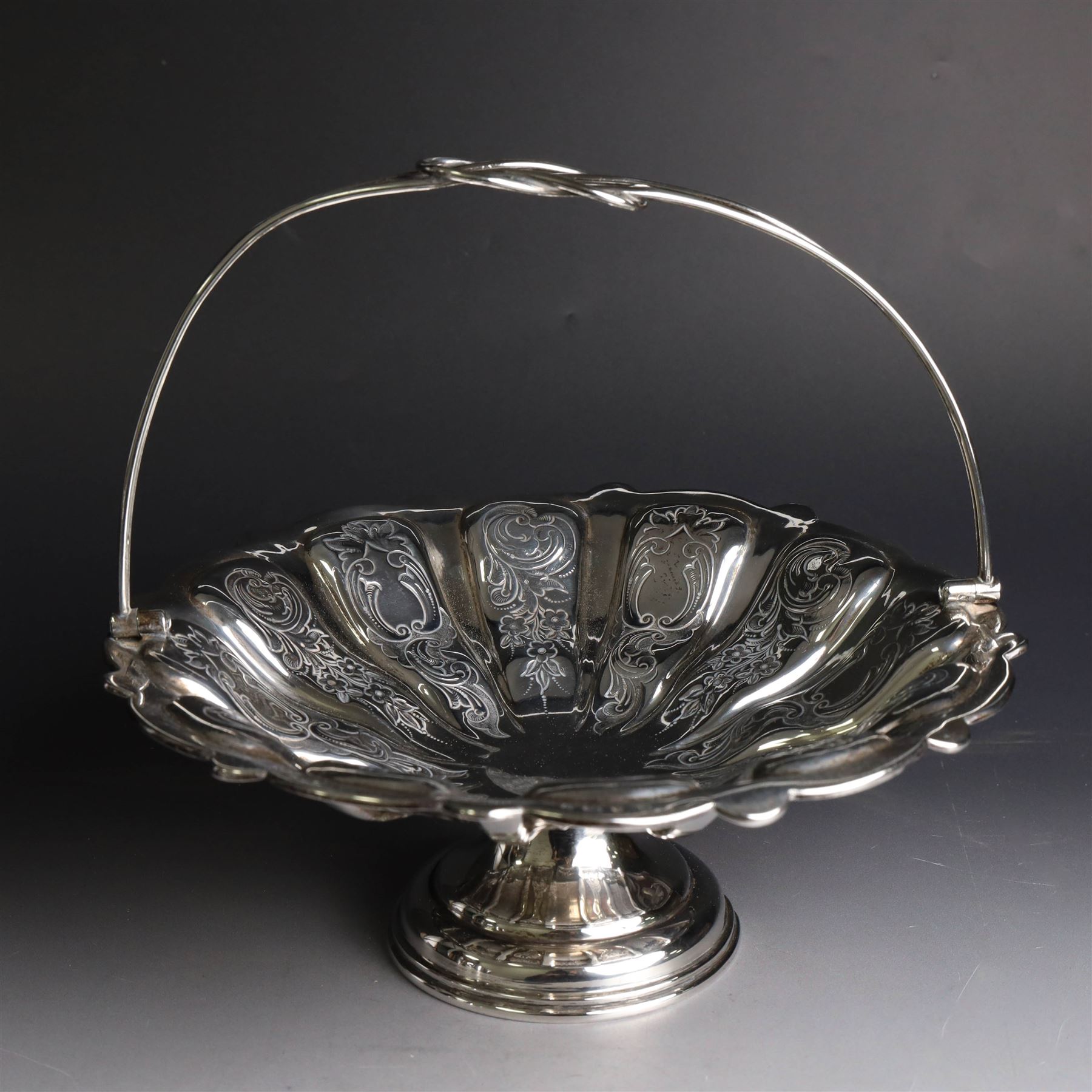 Edwardian silver swing handled basket, of circular form with shaped rim and engraved floral and foliate decoration, with know design swing handle and upon circular stepped pedestal, hallmarked J Sherwood & Sons, Birmingham 1901, H9cm, D22cm