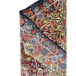 Persian Kirman indigo ground carpet, the field with repeating lozenge tiles with overall floral decoration, the main border with floral panels enclosed by the guards