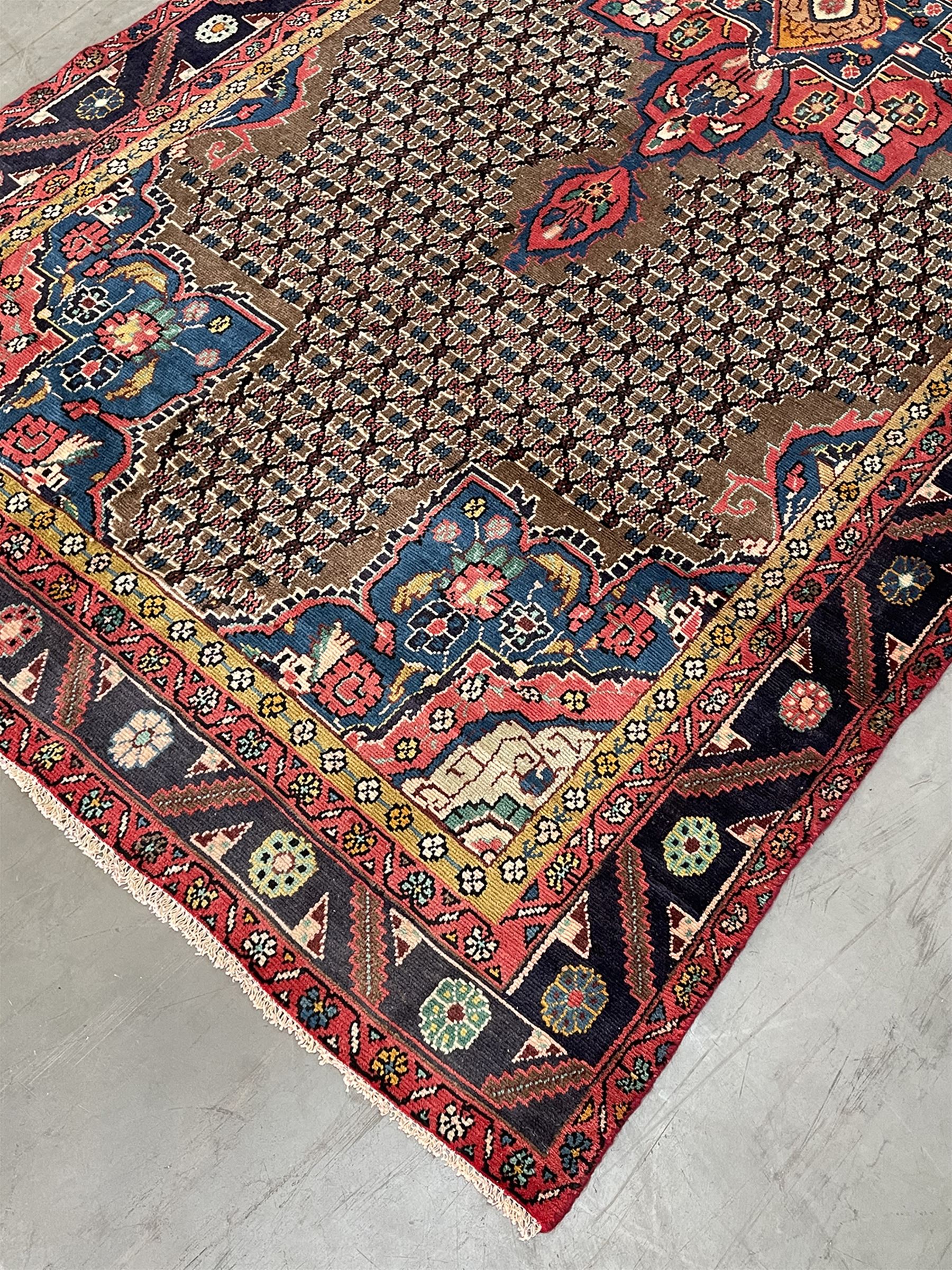 Persian Hamadan rug, the rosette pole medallion on a pale field decorated with stylised motifs, the blue band border decorated with stylised flower heads