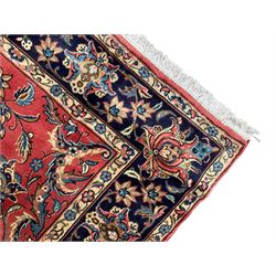 Persian Kashan red ground rug, the field decorated with trailing leafy branches and large palmettes, scrolling border decorated with stylised plant motifs and flower heads, within guard stripes