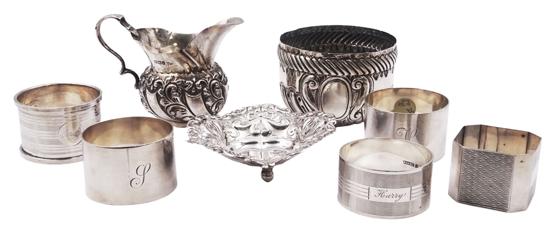 Group of five mid 20th century silver napkin rings, comprising a pair of plain circular form engraved with initial, hallmarked Viner's Ltd, Sheffield 1932, a circular example with engine turned bands, hallmarked R N Hollings & Co, Birmingham 1945, and two further 1930's examples, hallmarked Birmingham 1930 and 1934, various makers, together with a small early 20th century silver cream jug, of bellied form with foliate embossed decoration and scroll handle, hallmarked Walker & Hall, Sheffield 1910, including handle H6.5cm, etc.,  approximate total weight 8.98 ozt (279.3 grams)