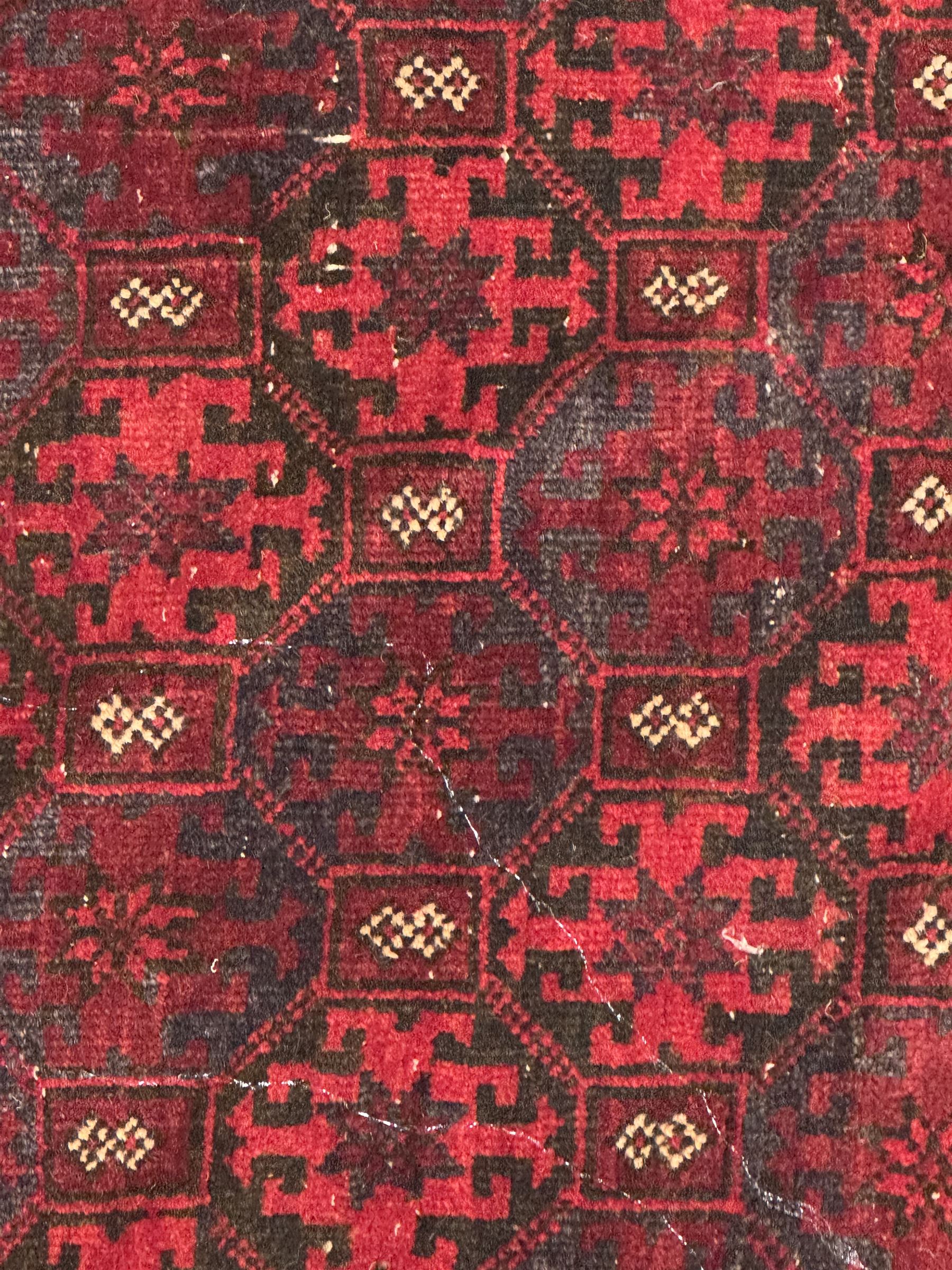 Turkoman red ground wool rug, the field with a repeating pattern of Tekke gul motifs in dark brown and red (195cm x 98cm); Afghan Bokhara red ground wool rug, central field with repeated geometric octagonal gul motifs, surrounded by multiple borders with stylised diamond and triangular patterns (127cm x 181cm)