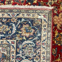 Persian Kashan red ground carpet, the field decorated with central medallion surrounded by trailing branches and stylised plant motifs, blue ground border with scrolling floral design 