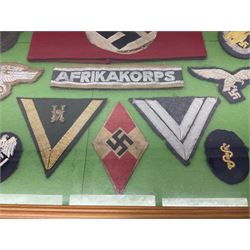 Framed display of thirty-four WWII German cloth badges including Luftwaffe pilot, Paratrooper, Afrikakorps cuff title, sleeve insignia for 'SS' Foreign Volunteers, various breast eagles including Luftwaffe, Army etc, RAD badges, Party Armband, rank and trade insignia, cap insignia etc; 40 x 50cm in modern pine frame