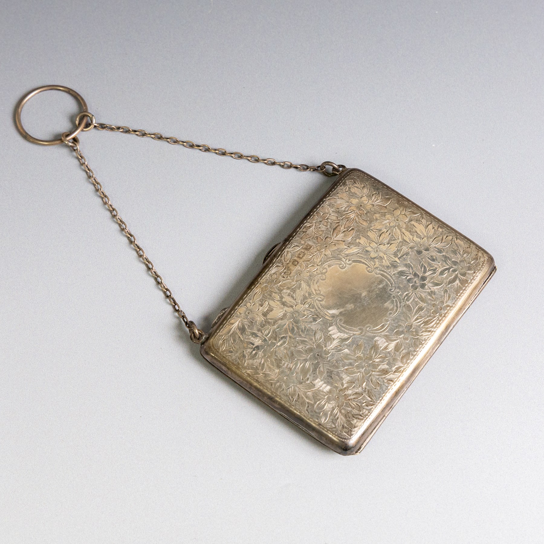 Early 20th century silver coin purse, with floral decoration and finger chain, hallmarked together with an early 20th century cigarette case,  with engraved initials, hallmarked and a silver filigree cigarette case
