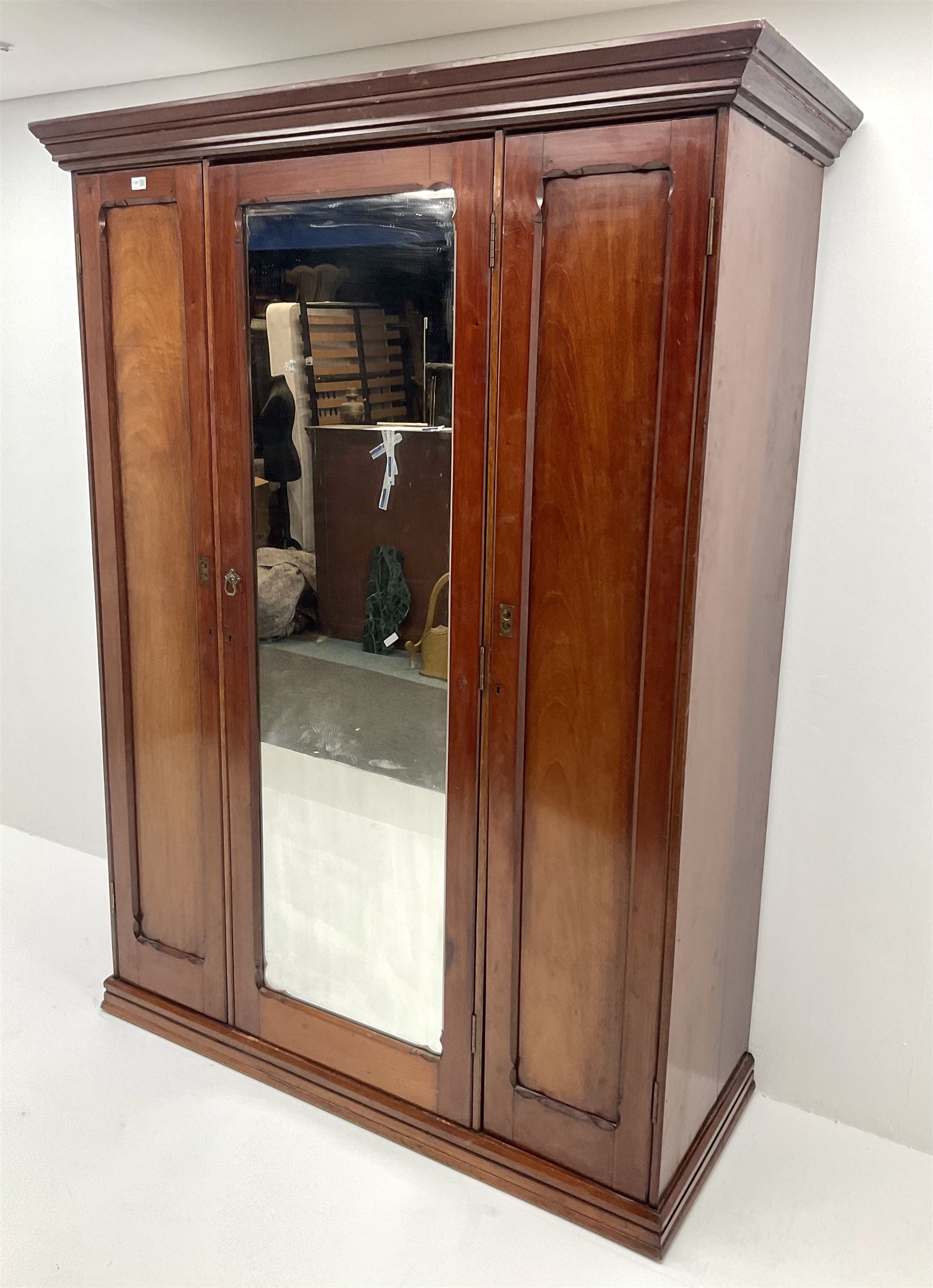 Victorian mahogany triple wardrobe, central mirrored door enclosing linen slides and two short and two long drawers flanked by two cupboards, plinth base
