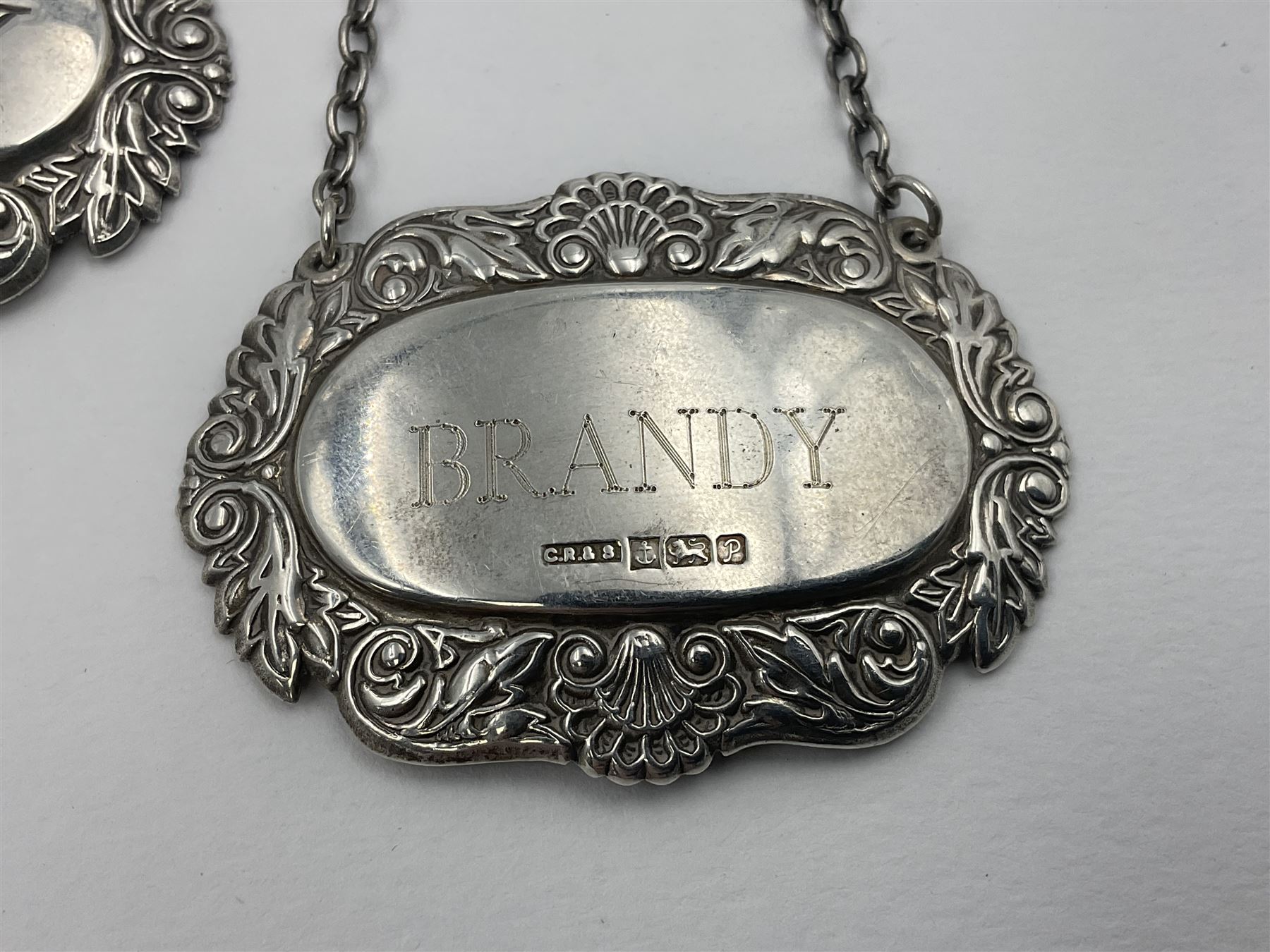 Five modern silver decanter labels, to include three similar Sherry and Brandy examples embossed with scrolls, two hallmarked C Robathan & Son, Birmingham 1989, and one hallmarked Laurence R Watson & Co, Birmingham 1987, together with a scotch example, hallmarked A Marston & Co, Birmingham 1970, and a larger sherry example, embossed with fruiting vines, hallmarked A Marston & Co, Birmingham 1993