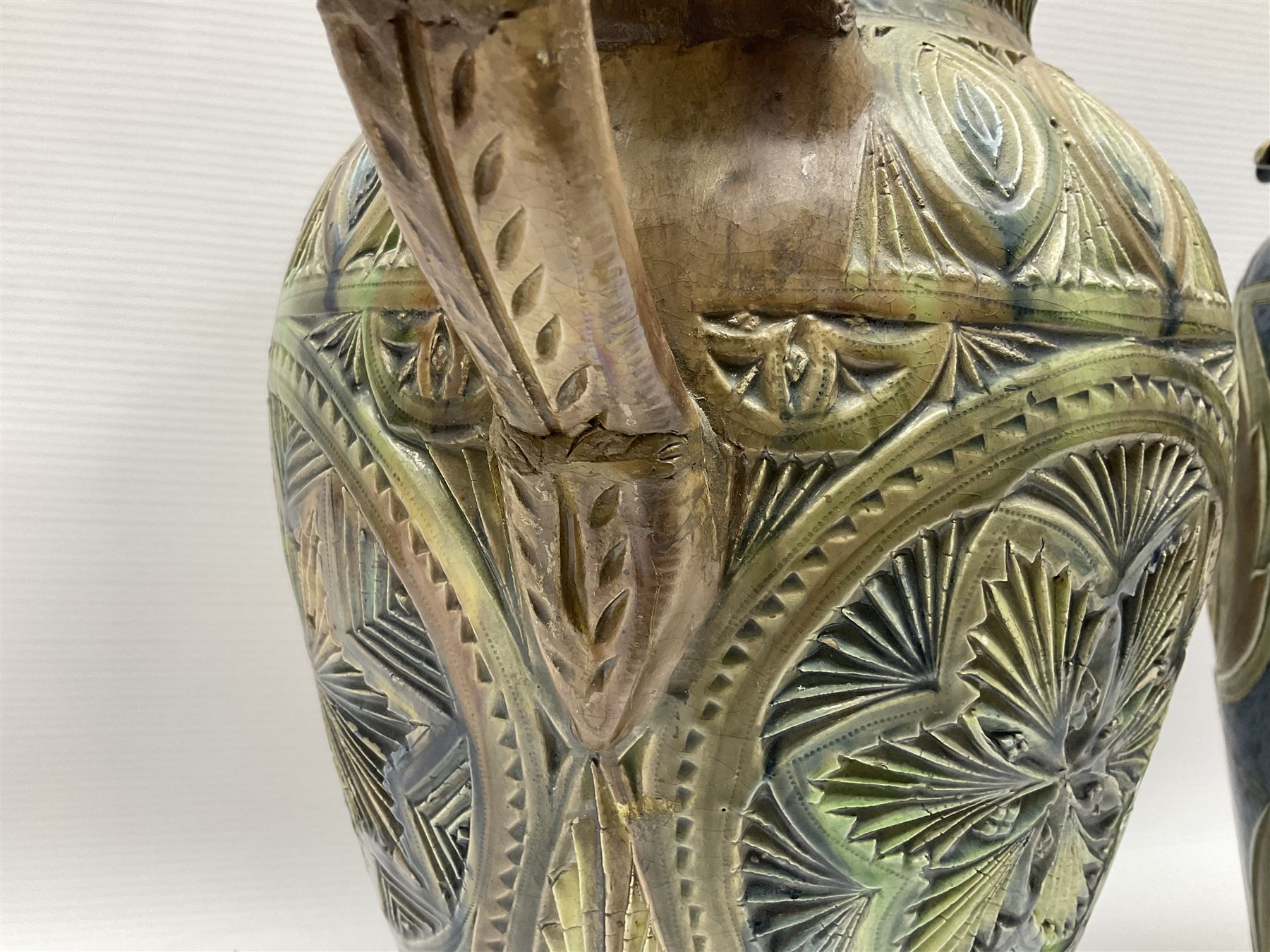Early 20th century Royal Doulton stoneware vase, decorated with a stylized floral design below a wavy rim, monogrammed B.N, possibly for Bessie Newbery, H28cm, together with an early 20th century glazed jug, heavily carved throughout (2)
