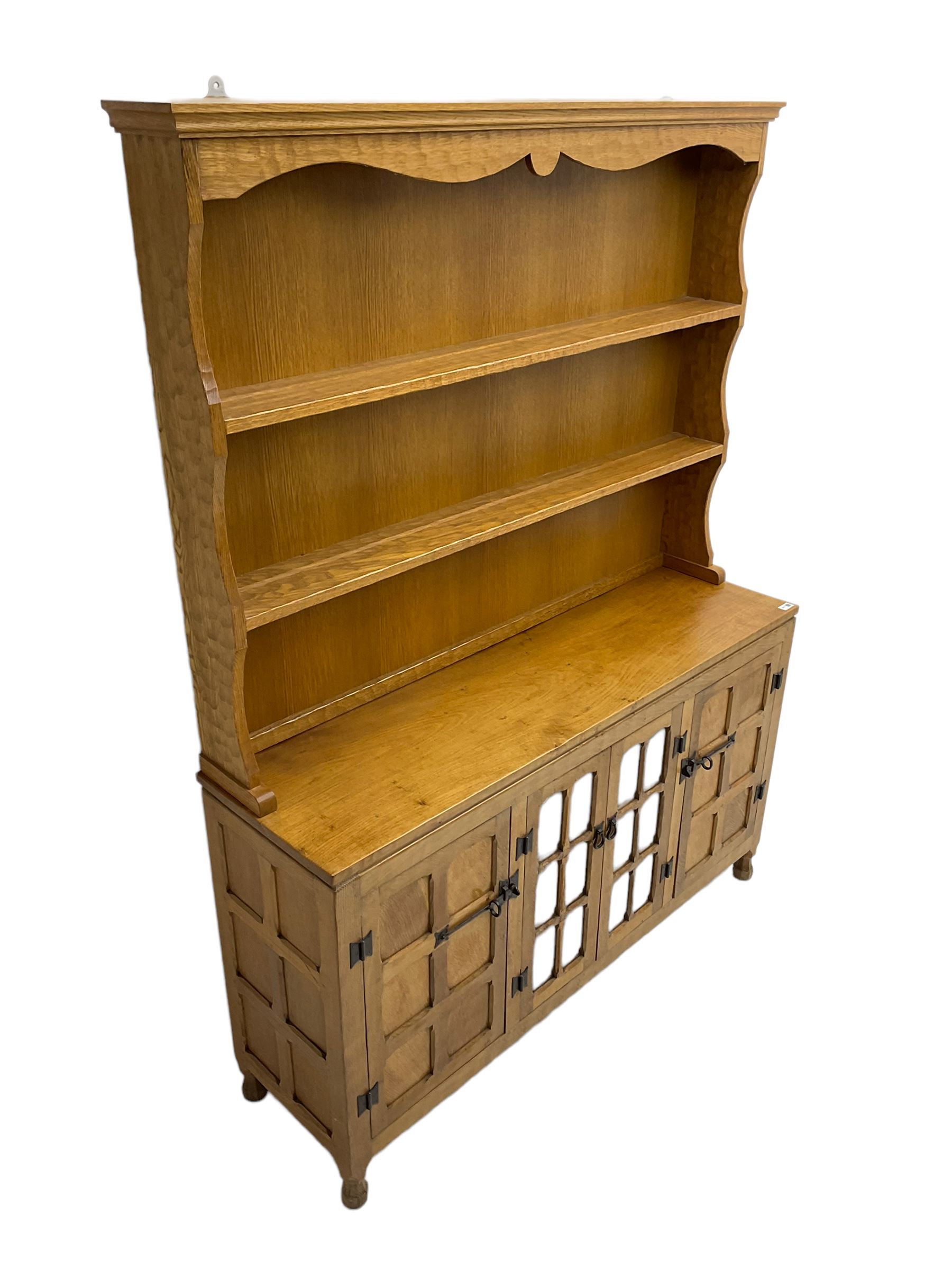 Yorkshire oak - adzed oak dresser, the rack with projecting cornice over shaped frieze and two shelves, the dresser fitted with central glazed double cupboard flanked by two panelled single cupboards, panelled sides