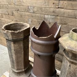 Collection of three Victorian and early 20th century reclaimed terracotta chimney pots, comprising: one cylindrical form with weathered, cracked glaze and flared octagonal base; one deep red cylindrical pot with fluted midsection and castellated rim, bearing moulded number ‘25’; and one tapering hexagonal example with wide flared rim and weathered patina. All with age-related wear and chips, consistent with use and outdoor exposure. Plus a selection of cast stone pieces including fountain 