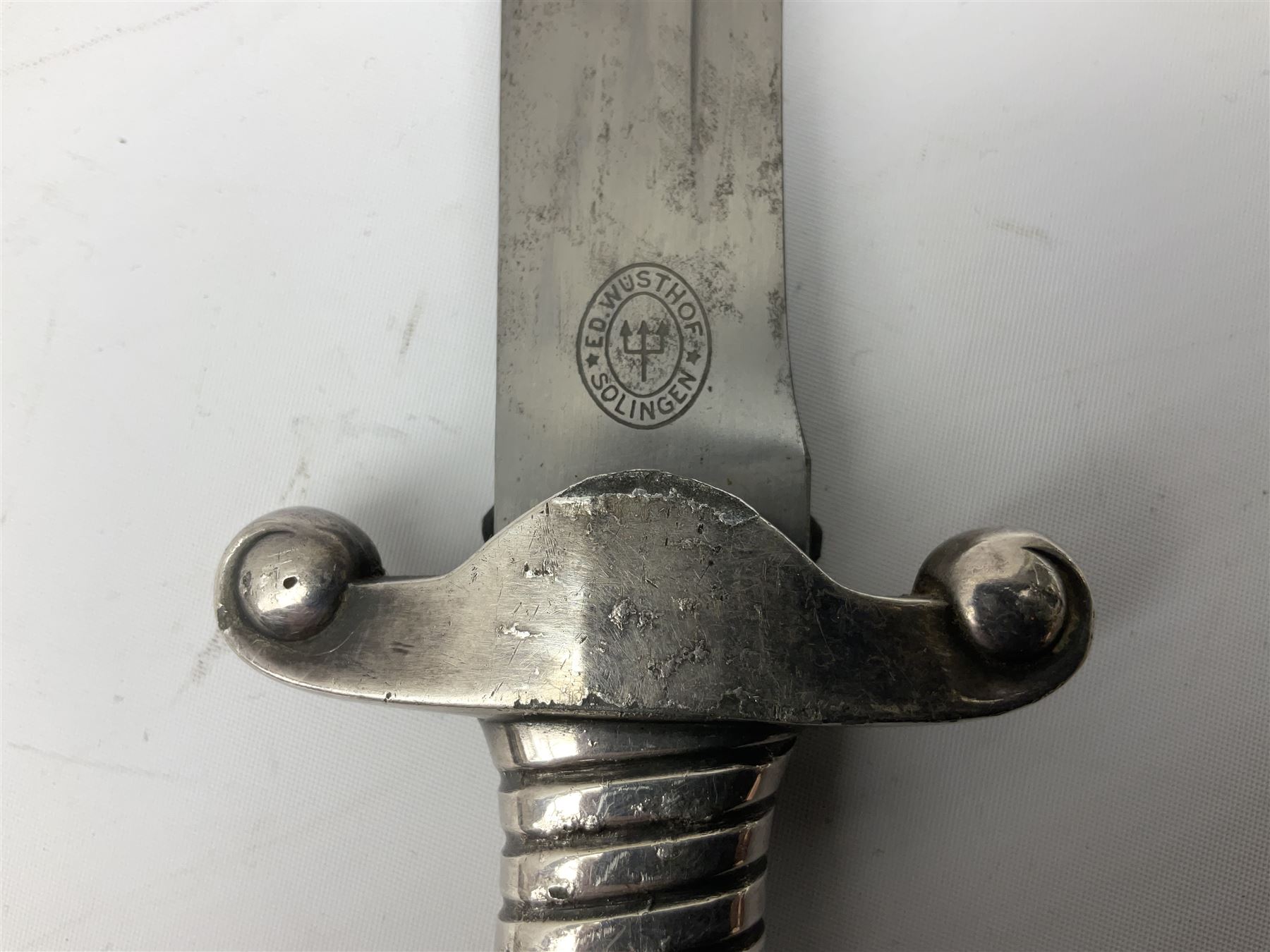 German Reichsarbeitdienst RAD Leader's Hewer dagger, the 26cm single edged scimitar shaped blade with narrow fuller, etched Arbeit adelt; by E.D. Wusthof, Solingen; the aluminium hilt with spade and wheat ear langet; two piece white plastic grip and eagle head pommel; pebbled steel scabbard engraved with ears of wheat and strapwork with double leather hangers L40cm overall