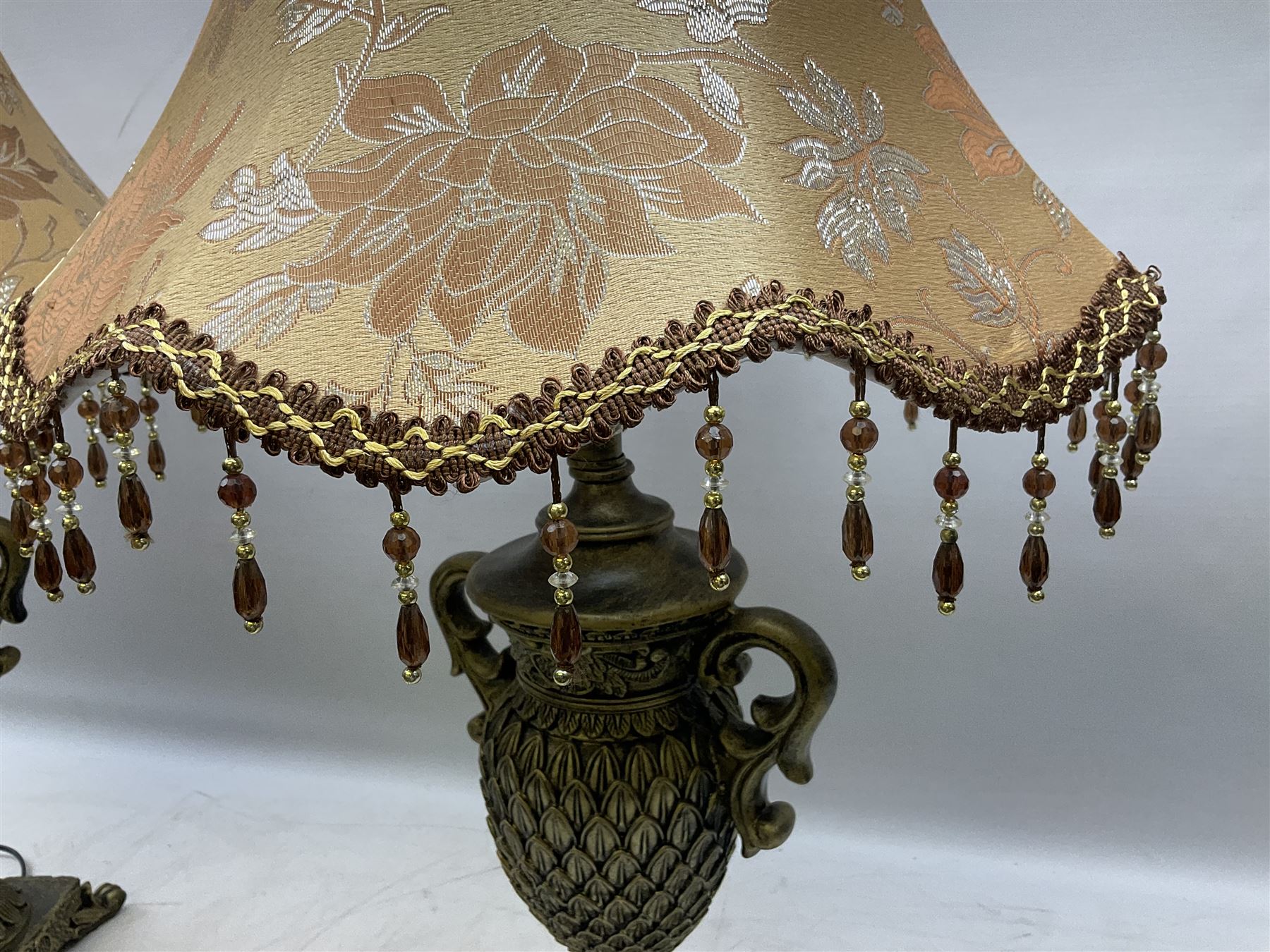 Pair bronzed amphora lamps with pineapple decoration, scroll handles and foliate base with scrolled feet together with pair peach ground shades and raised floral pattern H76cm (2)