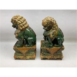 Pair of Chinese Temple Lions or Dogs of Foo, modelled in seated post, one with one front paw resting upon a ball, the other upon a cub, each upon stylised plinth base, H44cm
