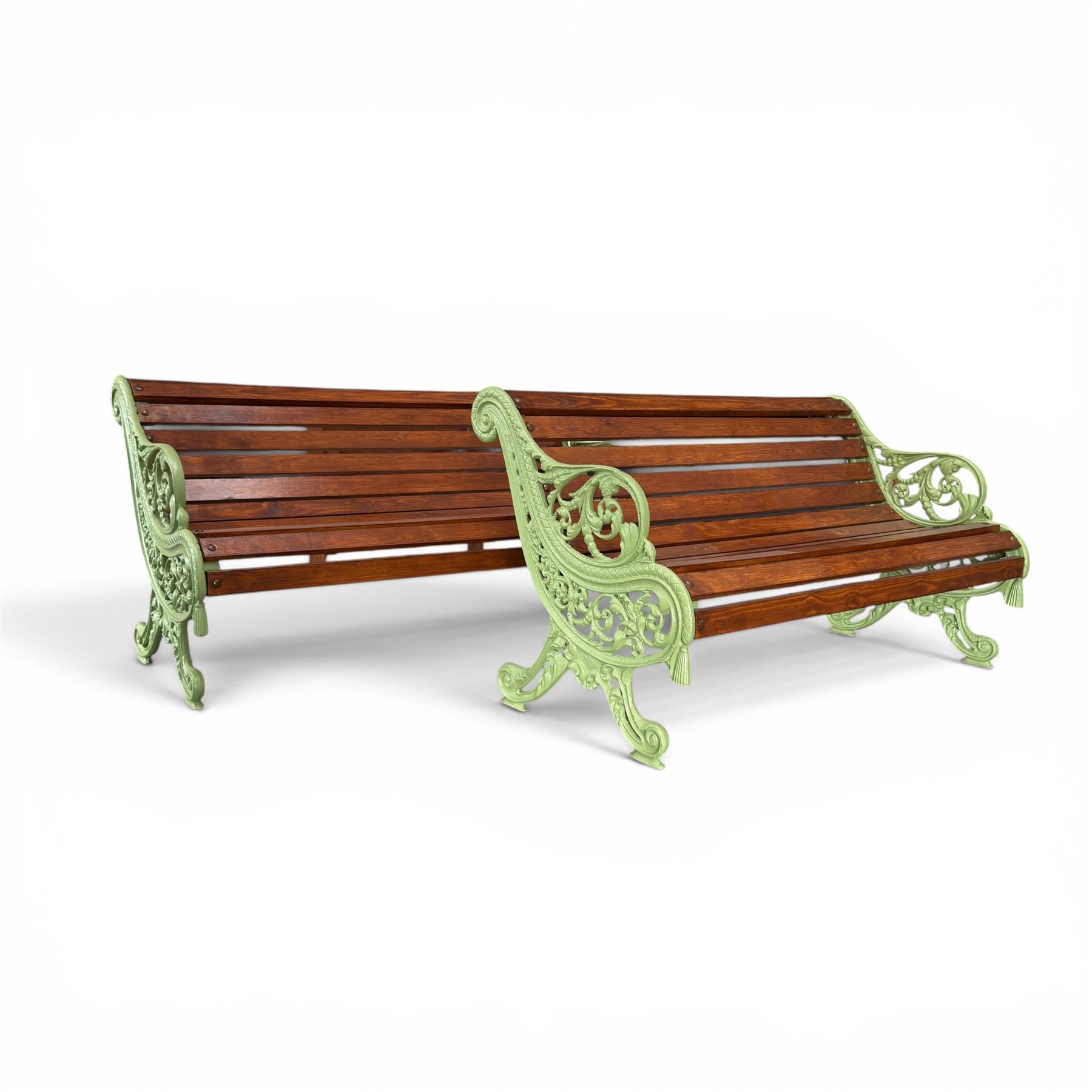 Pair of Victorian design cast iron and slatted wooden garden benches, the ornate pierced end supports of scrolled form, the pierced acanthus leaves interspersed with trailing flowerheads, with tassels to the front, raised on splayed feet, the supports in pale sage green painted finish