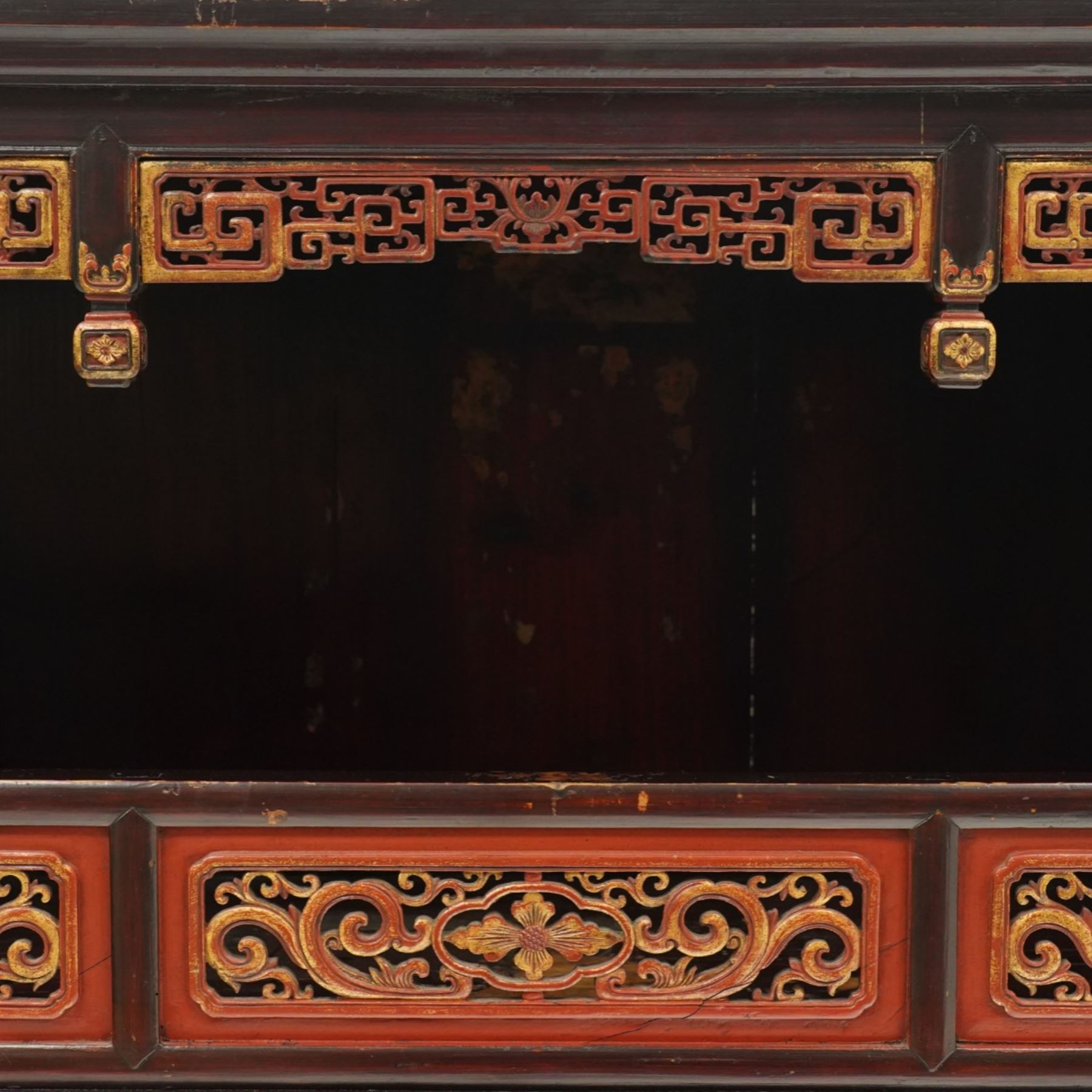 Chinese black lacquer Buddha cabinet, moulded top over open display recess framed by pierced geometric fretwork and corner spandrels, the base fitted with an arrangement of five drawers with carved and gilt scrollwork panels, on square supports with shaped apron brackets