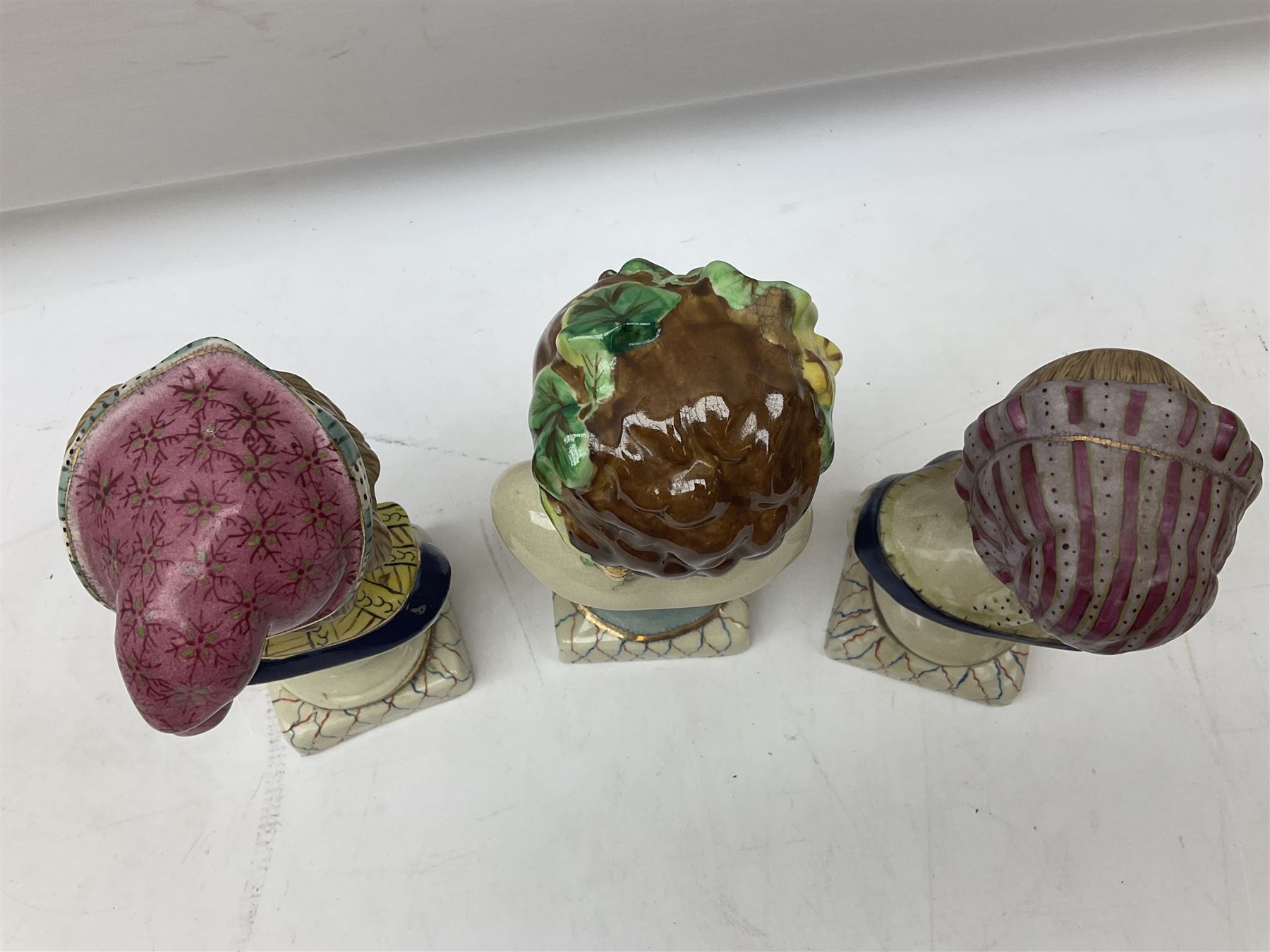 19th century pair of hand painted ceramic busts of children, together with a third similar example of a putti with a crown of ivy, tallest H23cm 