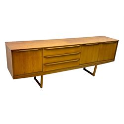 Mid-20th century teak sideboard, fitted with a fall-front cupboard, three drawers including a green baize-lined cutlery drawer, and a double cupboard, with integrated handles, on sleigh supports