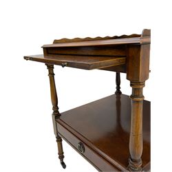 Figured walnut two tier occasional table, raised scalloped gallery on square moulded top, fitted with slide and undertier with drawer, turned supports on castors