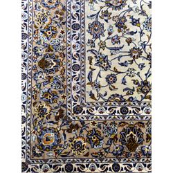 Central Persian Kashan hand-knotted carpet, ivory field with an all-over design of scrolling vines, lotus palmettes, and rosettes in shades of blue, gold, and brown within a blue ground border of palmettes and arabesques between multiple guard stripes