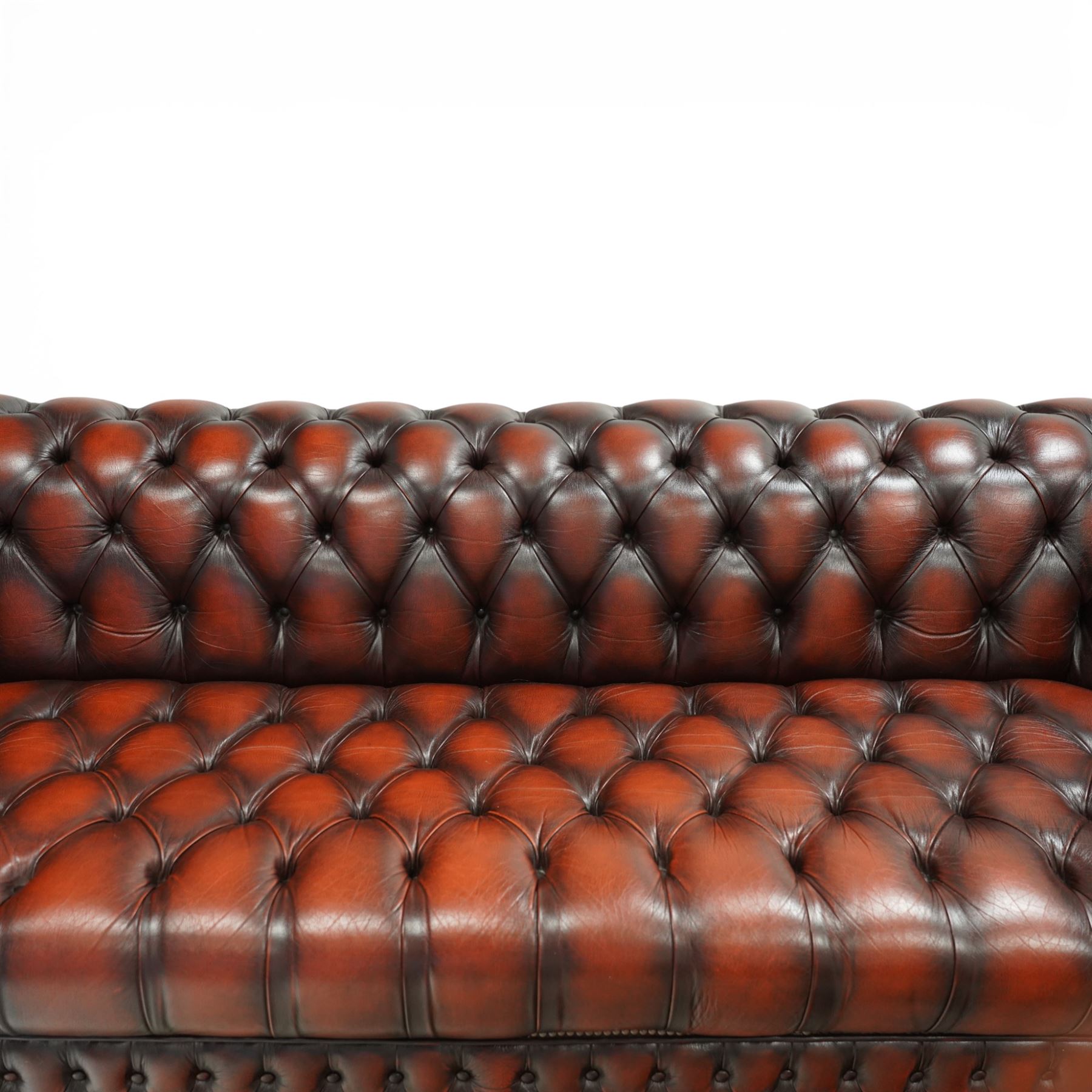Late 20th century four seat Chesterfield sofa, upholstered in deep buttoned brown leather, with rolled arms, buttoned back and seat, studded detailing and squat feet