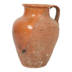 Three early 20th century Spanish part glazed terracotta storage vessels, the first example of bellied form with rounded base and twin loop handles, H24cm, the second of baluster for with close set loop handles, H30cm, and the third smaller also of baluster form with single loop handle, H24cm