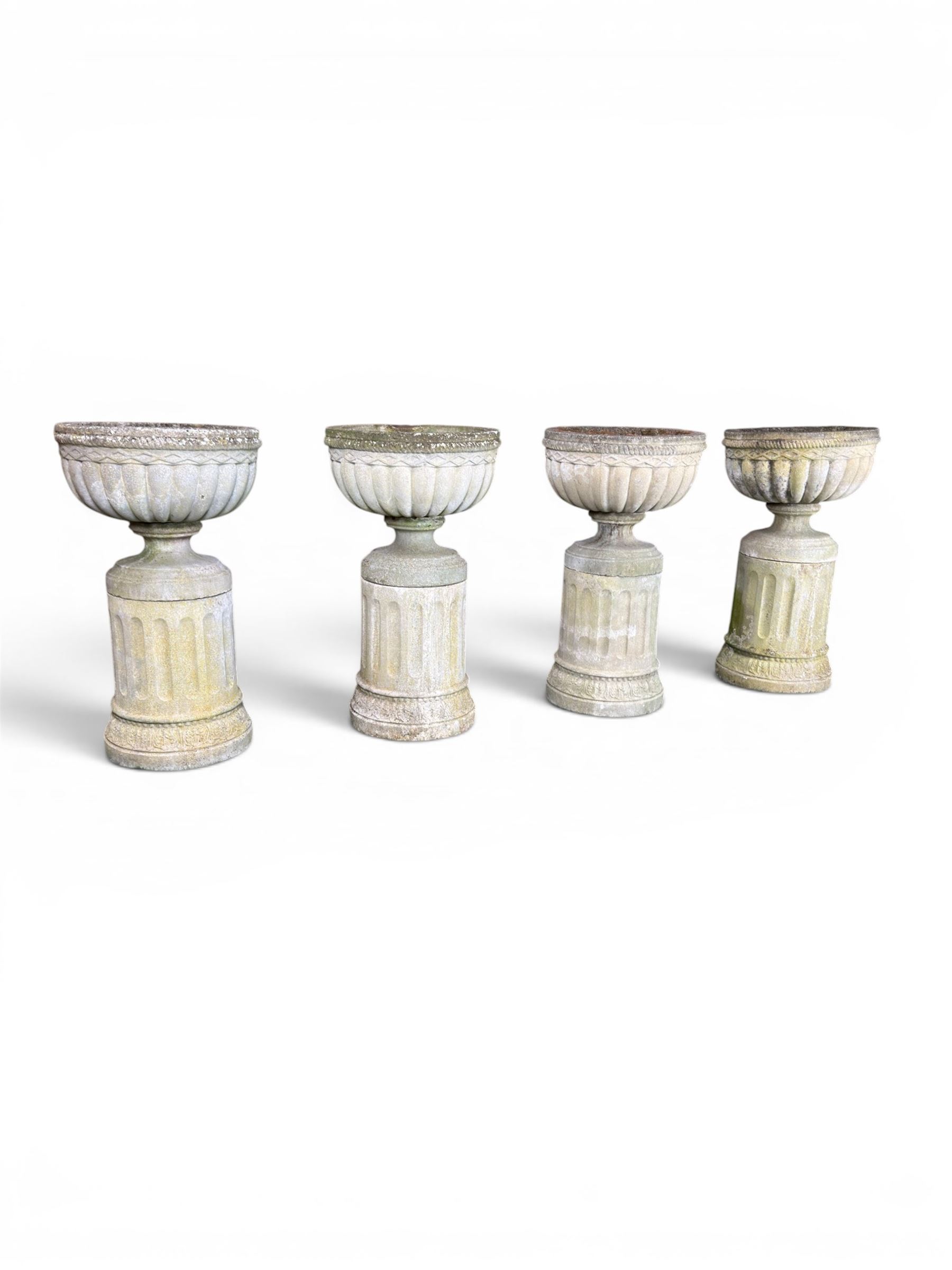 Four 20th century good quality weathered cast stone pedestal urns, circular lobed bowls with rope twist and lattice border, raised on squat base with fluted columns