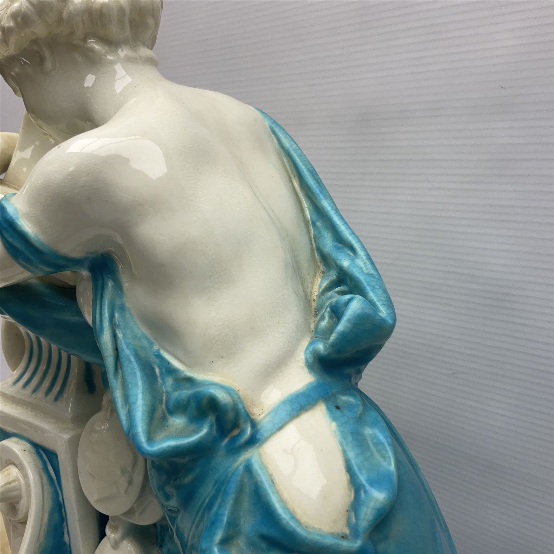 Rare 19th century Minton turquoise glaze majolica 'The Reader' flower holder, after Albert Carrier-Belleuse, modeled as a maiden in classical drapery reading whilst leaning against the pillar back of the helmet shaped cistern detailed with a caryatid and floral swags, the whole upon an oval plinth with Greek key border, with impressed marks beneath, H44cm