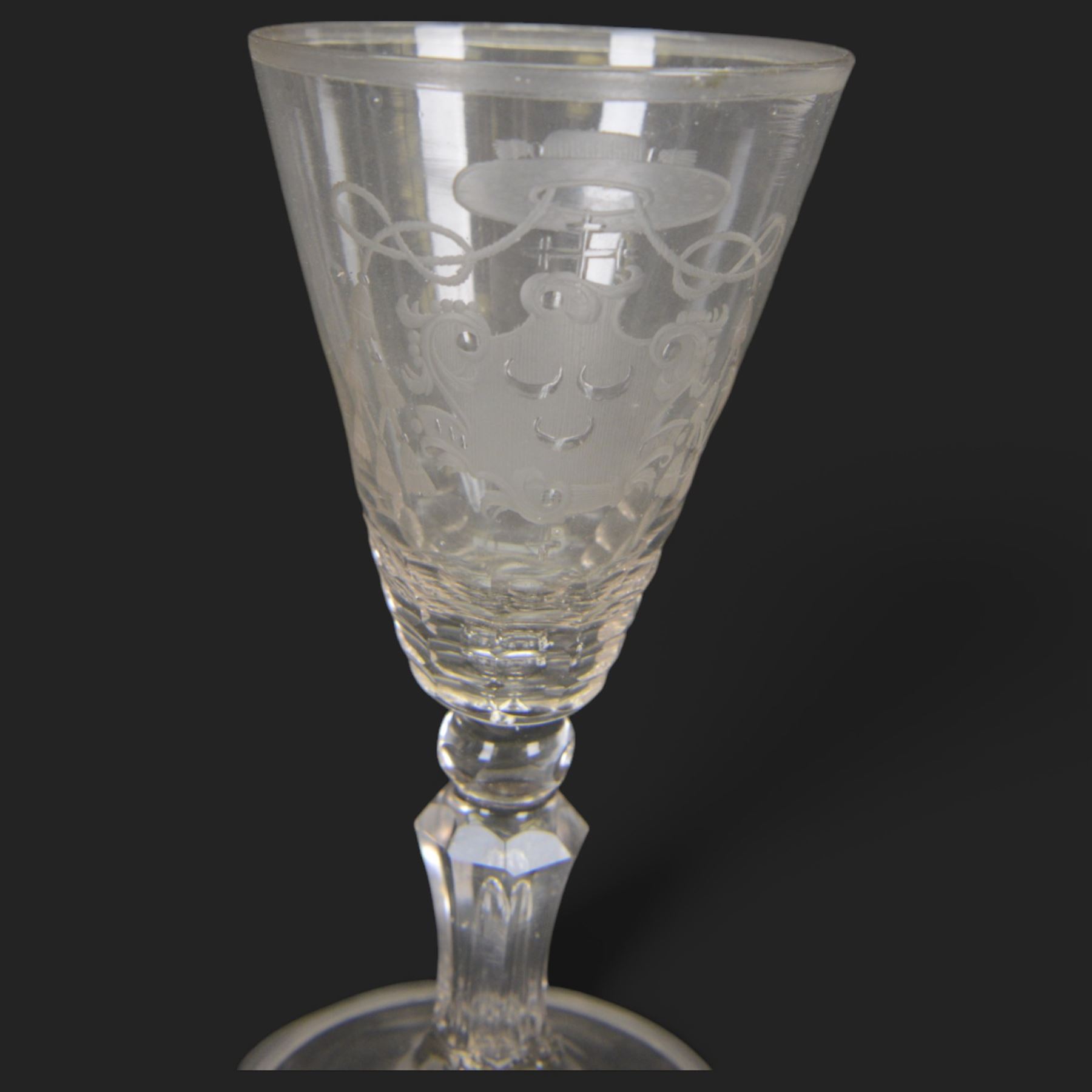 Two 18th century Continental facet cut drinking glasses, each with funnel bowl engraved with armorial type cartouche, upon a knopped and facet cut stem with internal elongated tear, and spreading folded foot, largest H15.5cm
