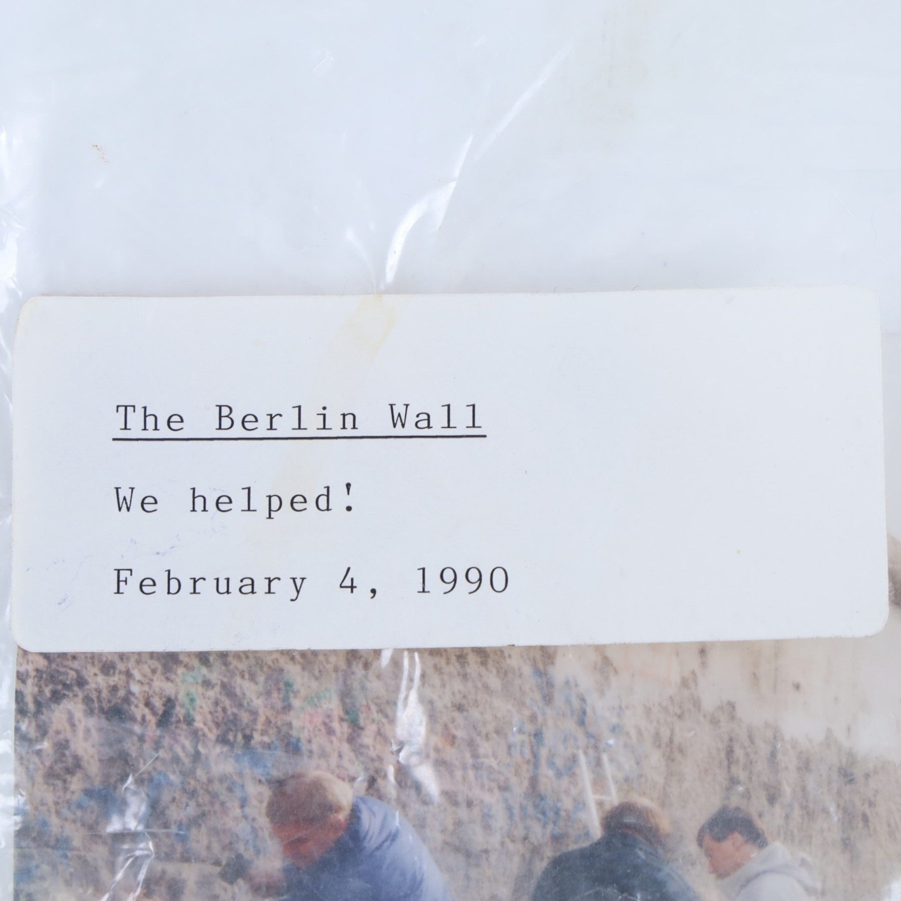 Fragment of the Berlin Wall, largest piece with blue paint to one side, with photograph and sticker to bag dated 1990