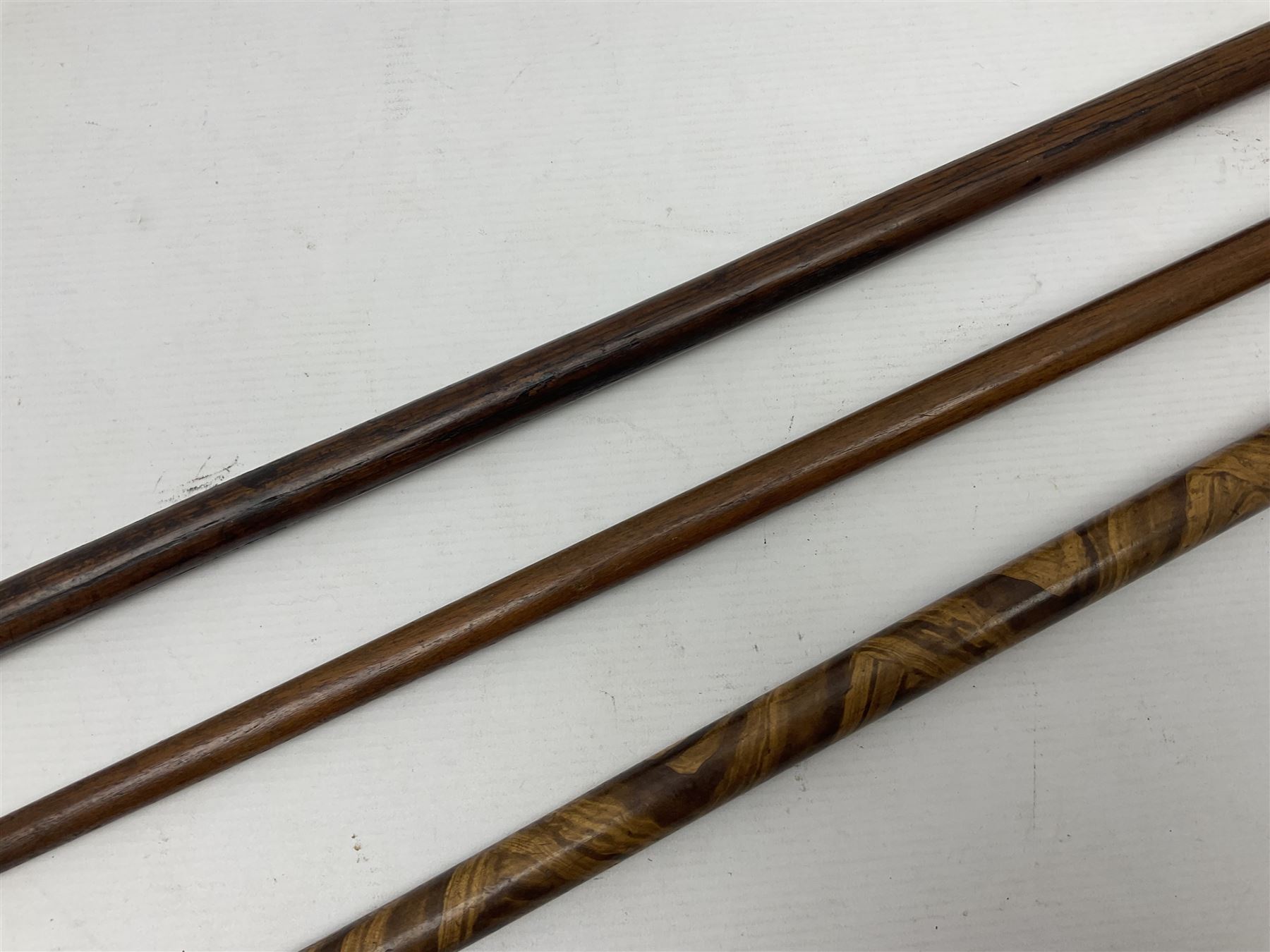 Three early 20th century walking sticks, to include a smoking pipe walking stick, the cane opening to reveal a concealed pipe, and a wooden walking cane, the metal cover with inscription 'bell metal and wood of York Minster, Burnt May 20 1840, and a turned wooden walking stick, with marquetry checkerboard pommel, tallest L90cm