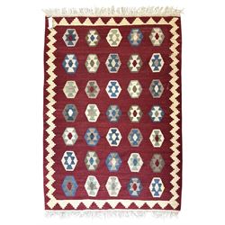 Handwoven wool Kilim rug of rectangular form with cream fringe, the red ground decorated w...