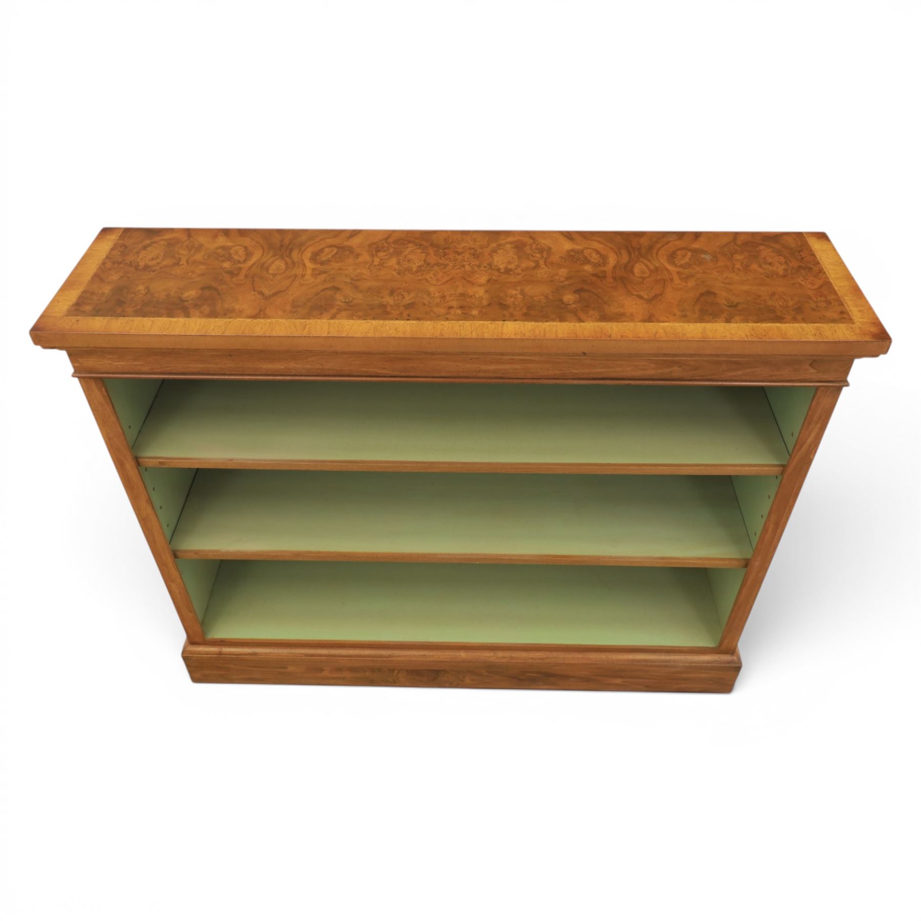 Traditional walnut small bookcase, with projecting cornice above a green painted interior, adjustable shelving, on a moulded plinth base