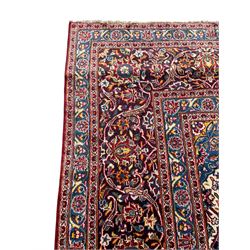 Large Persian Kashan crimson ground carpet, large floral central medallion surrounded by trailing branches decorated with leaves and stylised plant motifs, the main border with scrolling design interspersed with palmettes, within floral pattern guard stripes 