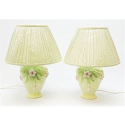 A pair of Italian ceramic lamps, of baluster form, the light green glaze detailed with pink flowers, with pleated light green shades, overall H45cm.