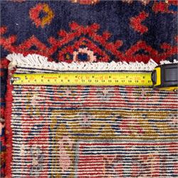 North West Persian Cirjan hand-knotted rug, indigo field decorated with vertical columns of stylized boteh, rosettes and diamond devices arranged in a repeating lattice and a chain of linked lozenges, enclosed by a mustard gold inner border and a principal border of madder ground, flanked by narrow guard stripes, with cotton fringe ends 