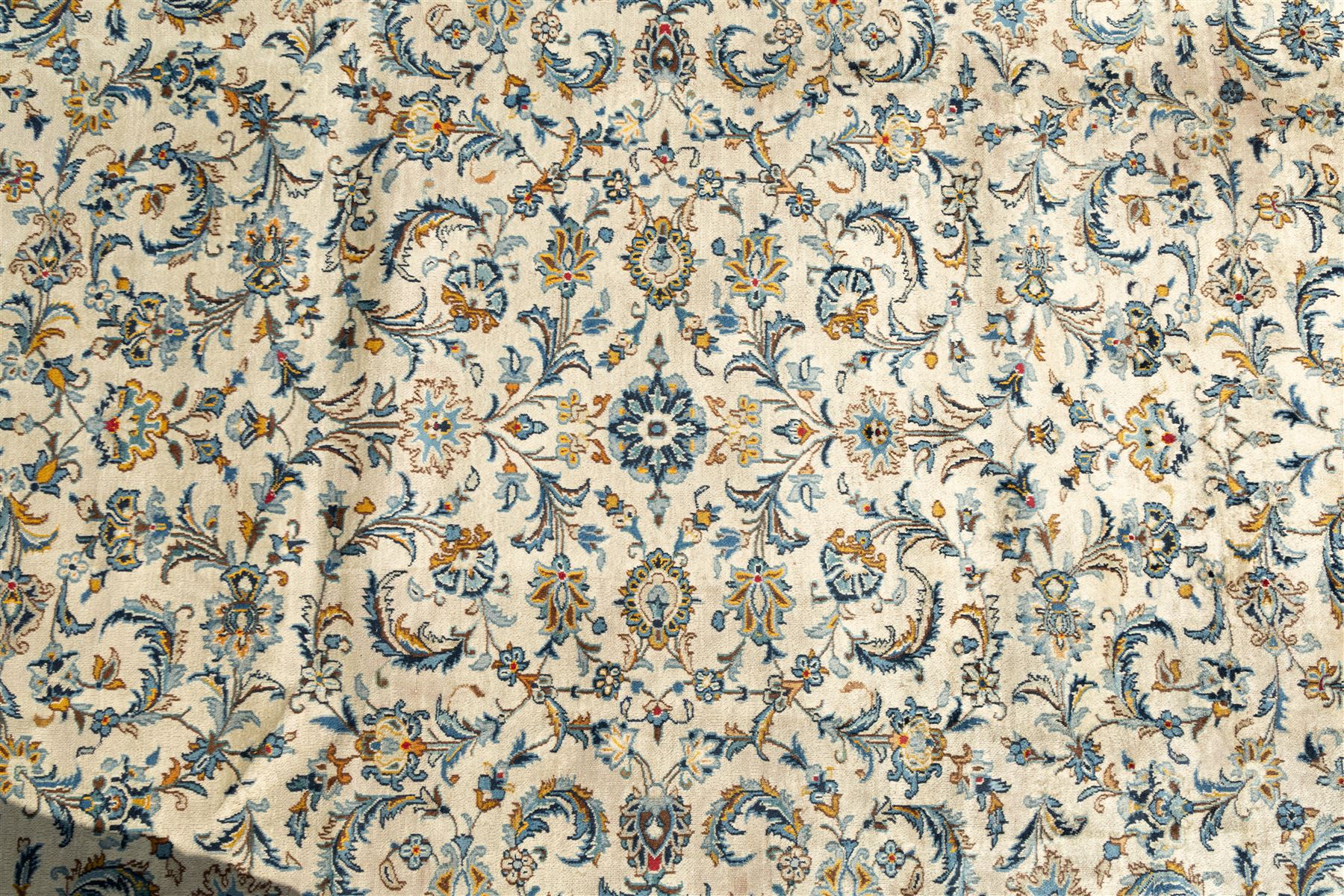 Central Persian Kashan hand-knotted carpet, ivory field profusely decorated with an all-over scrolling vine, palmette, and lotus design in shades of soft blue, pale gold, and green within floral borders